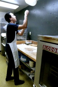 Cook Marco tosses pizza dough for waiting customers.