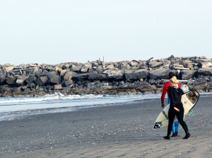 Surfers walk down the beach at "the jetty."