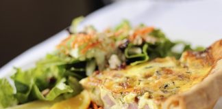 wedge of quiche on a plate with a side salad