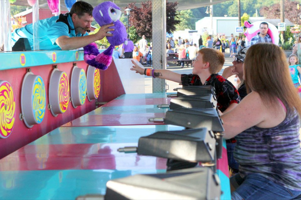 kid playing a carnival game and getting handed a prize