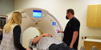 a person lying on a CT scanner with technicians standing on either side