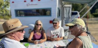 two men and two women sitting at a table playing cards outside their RV at Friends Landing near the Washington Coast