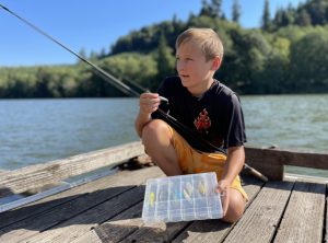 little boy puts a lure on his fishing rod while camping near the Washington Coast at Friend's Landing