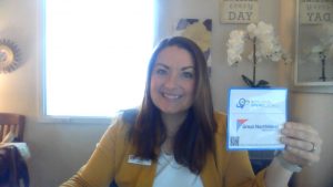 Karla Peterson, marketing & community development manager holding the Buy Local Spend Local sticker.