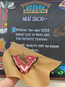 fresh, heart-shaped steak on brown paper with herbs on top