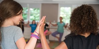 Two girls touching their palms together while doing yoga
