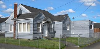 grey one story house with a chain link fence