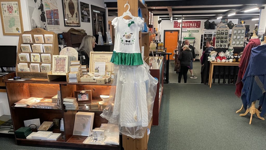 stationary, a little girl's dress with a green skirt and white top with a sheep on it that says, 'Ireland' and dozens more items on the shelves and racks at Galway Bay