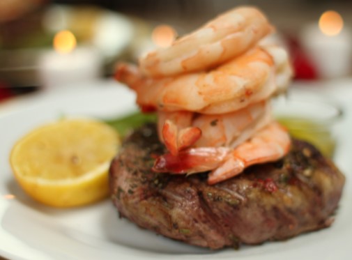 steak with two shrimp on top and a lemon slice next to ir