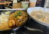 plate of pad thai, bowl of some type of thai soup with two boba tea drinks in the background