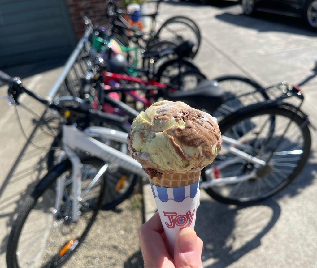 a hand holding an ice cream cone with bikes in the background