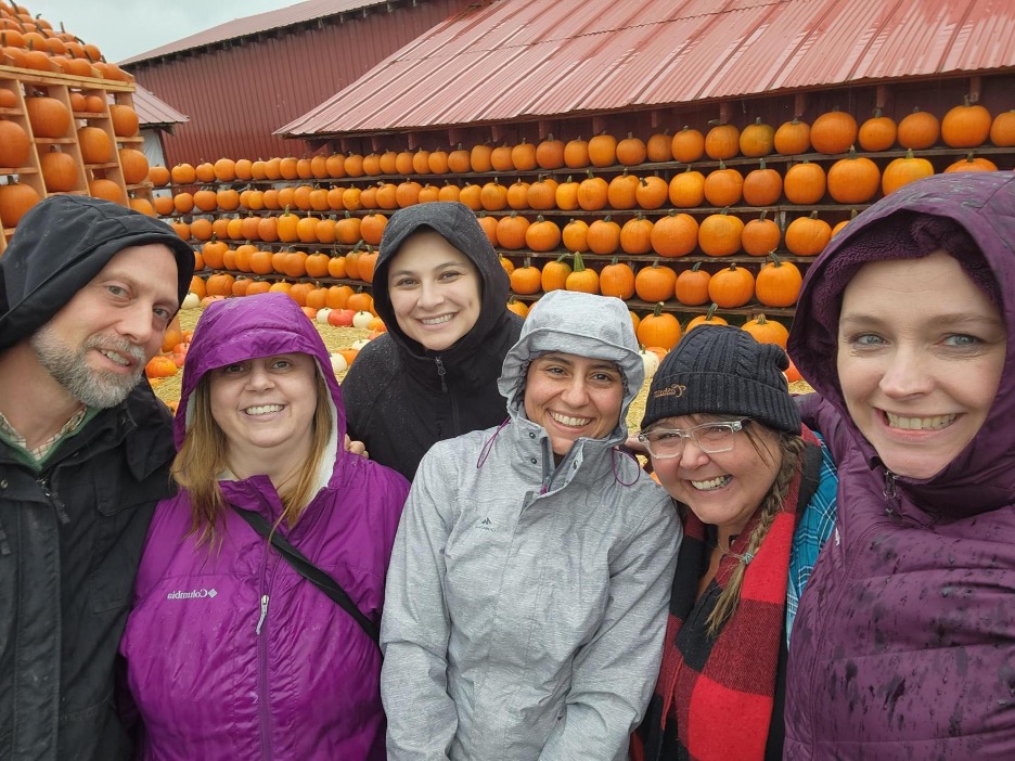 Group of Summit Pacific's Health Team at a pumpking patch, with rows of pumpkins on shelves behind them.