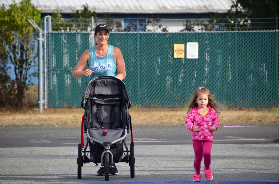 women running with a stroller and a little girl next to her