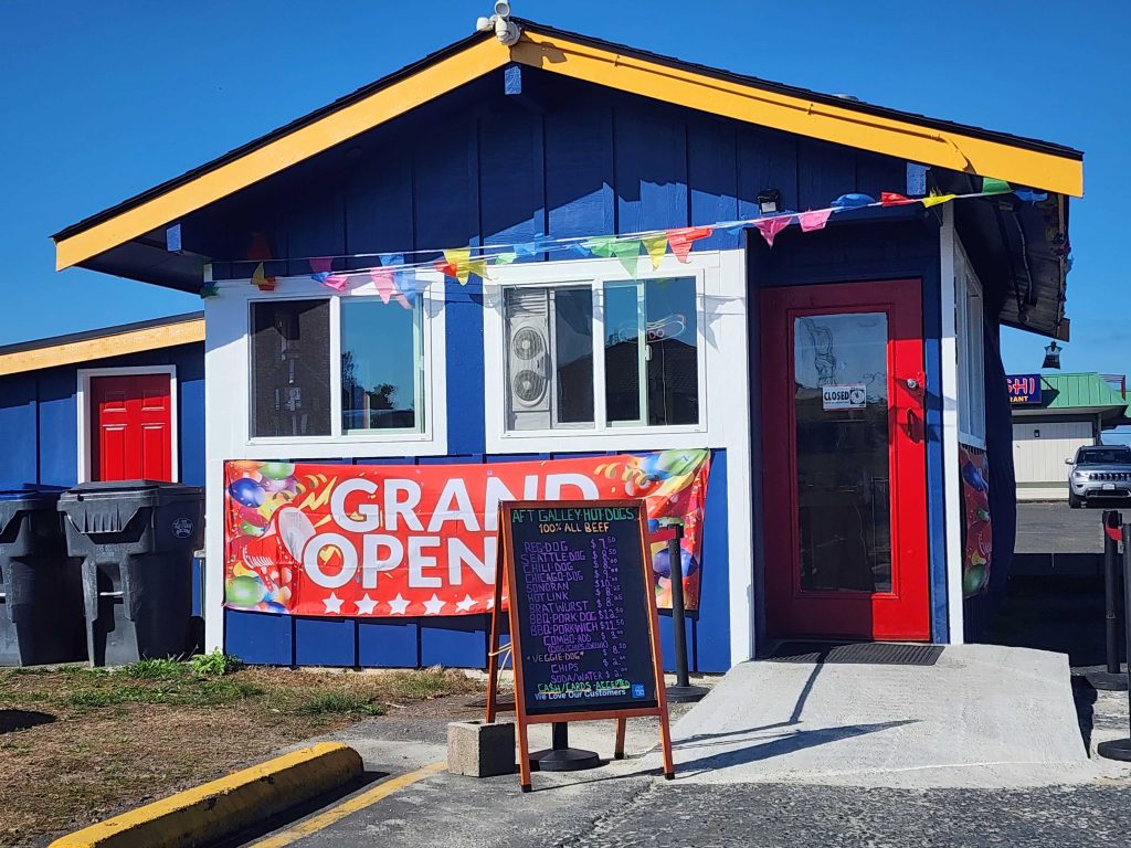 OUtside of Aft Galley Hot Dogs with a banner that says 'Grand Opening'