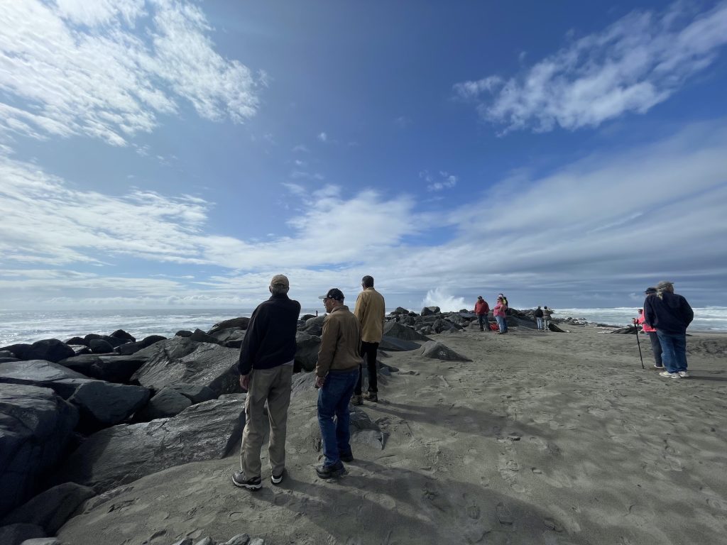 small group of people standing on a Grays Harbor Beach looking at the waves
