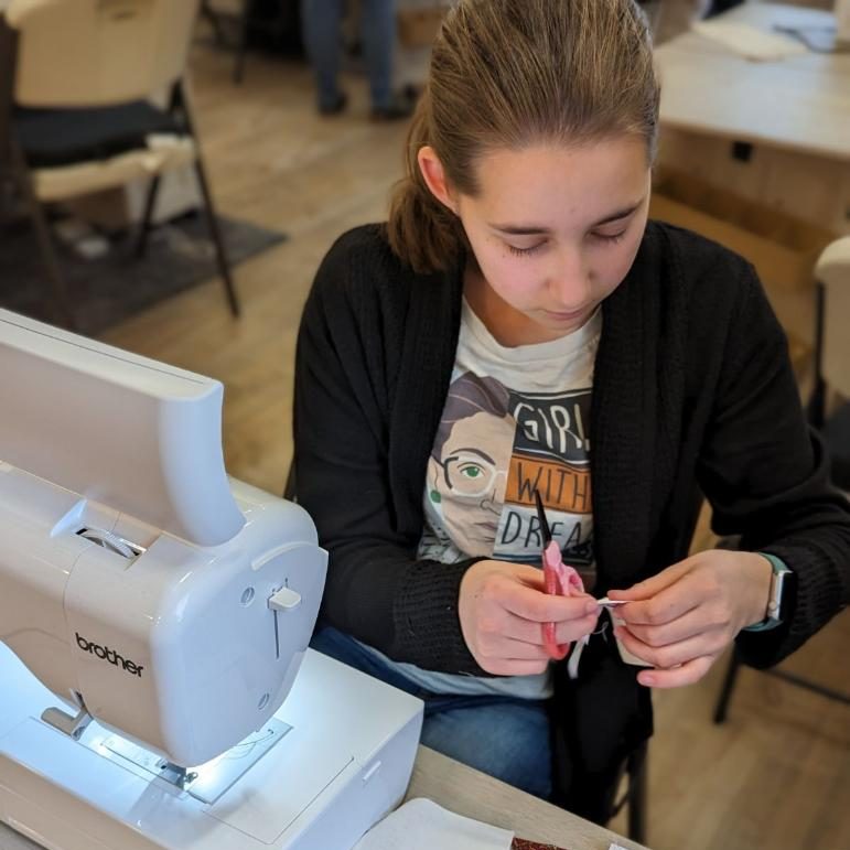 Lucy sitting at a table with a sewing machine, working on quilt blocks