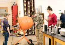 three college students work on a piece of equipment in the Saint Martin's University Civil Engineering department