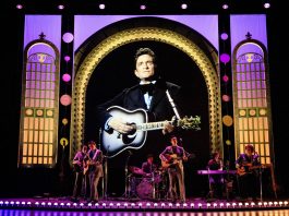 Stage with band performing with photo of Johnny Cash