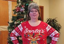 DeDe Hoer in an ugly Christmas sweater standing in front of a Christmas tree