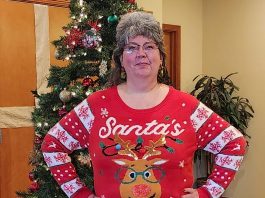 DeDe Hoer in an ugly Christmas sweater standing in front of a Christmas tree