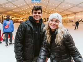 a man and woman pose for a picture inside the Oly on Ice rink