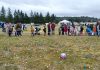 people lined up in a field sprinkled with plastic eggs