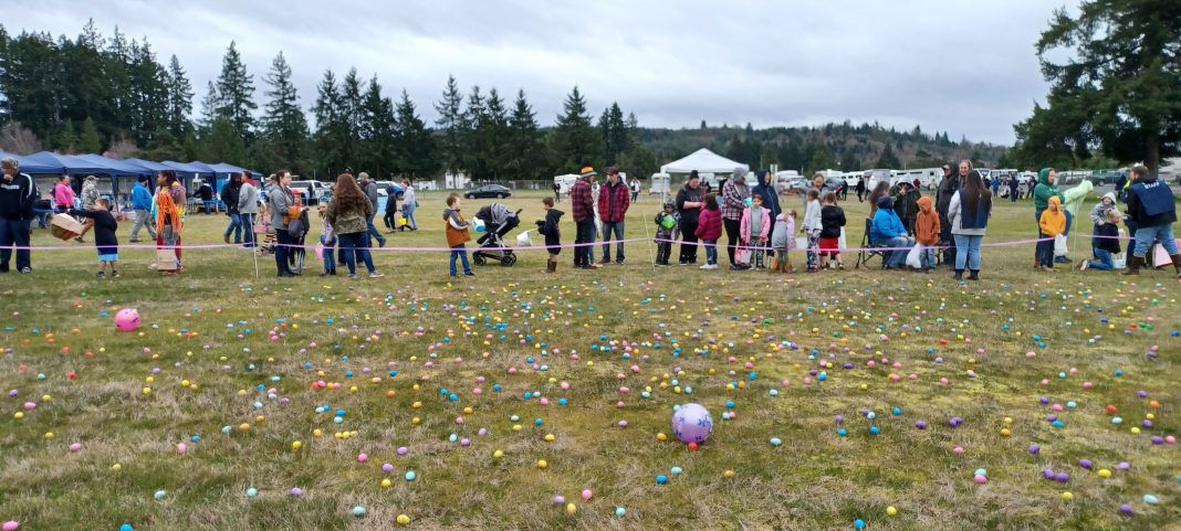 people lined up in a field sprinkled with plastic eggs