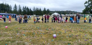 people lined up in a field sprinkled with plastic eggs