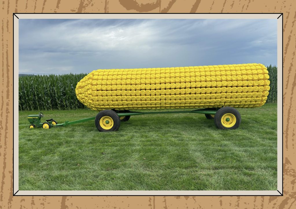 giant fake corn on the cob on wheels sitting in a field