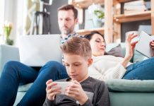 a man, woman and child, in a living room all on computer, tablets or phones