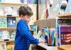a small boy looks at a book on a short bookshelf in harbor books