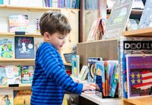 a small boy looks at a book on a short bookshelf in harbor books