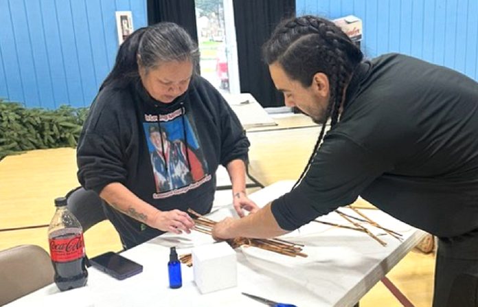 TAALA Fund-Cedar-Root-Business-Center-Artist-Table-2 (2) a man and a woman work on putting together something with sticks on a table