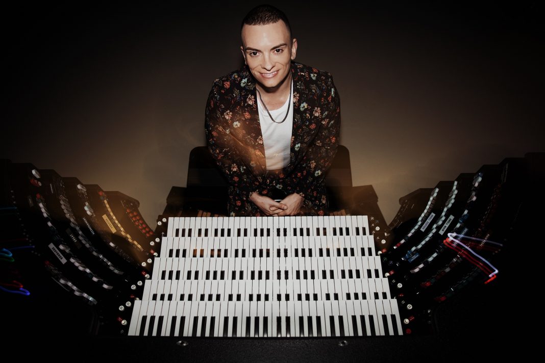 Cameron Carpenter sitting at an organ facing the camera